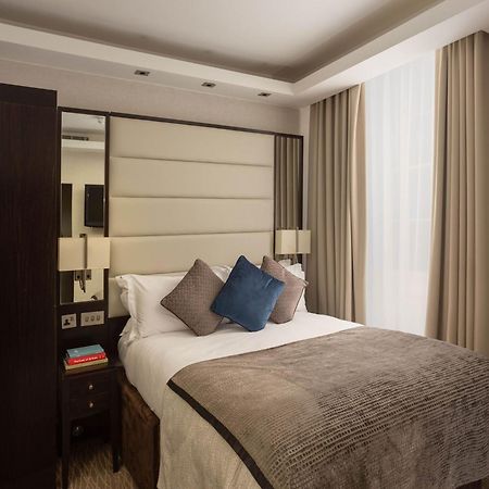 Hotel Montcalm Brewery Townhouse Londýn Exteriér fotografie The image shows a cozy bedroom. It features a comfortable double bed with a light-colored duvet and decorative pillows in shades of blue and gray. The headboard is upholstered in a soft material, and there are bedside lamps on either side of the bed.