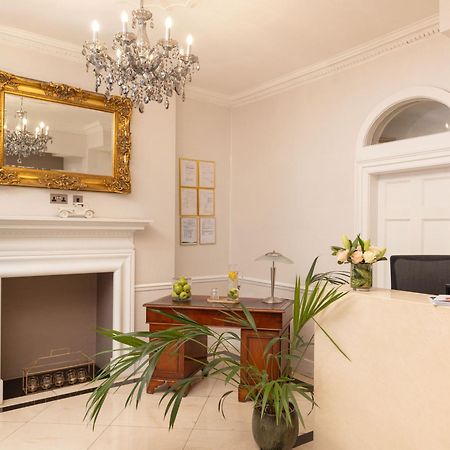 Hotel Montcalm Brewery Townhouse Londýn Exteriér fotografie The photo shows a stylish reception area. There is a decorative chandelier hanging from the ceiling, providing elegant lighting. A large, ornate mirror is mounted on the wall beside the fireplace, which features a simple, classic design. In front of 