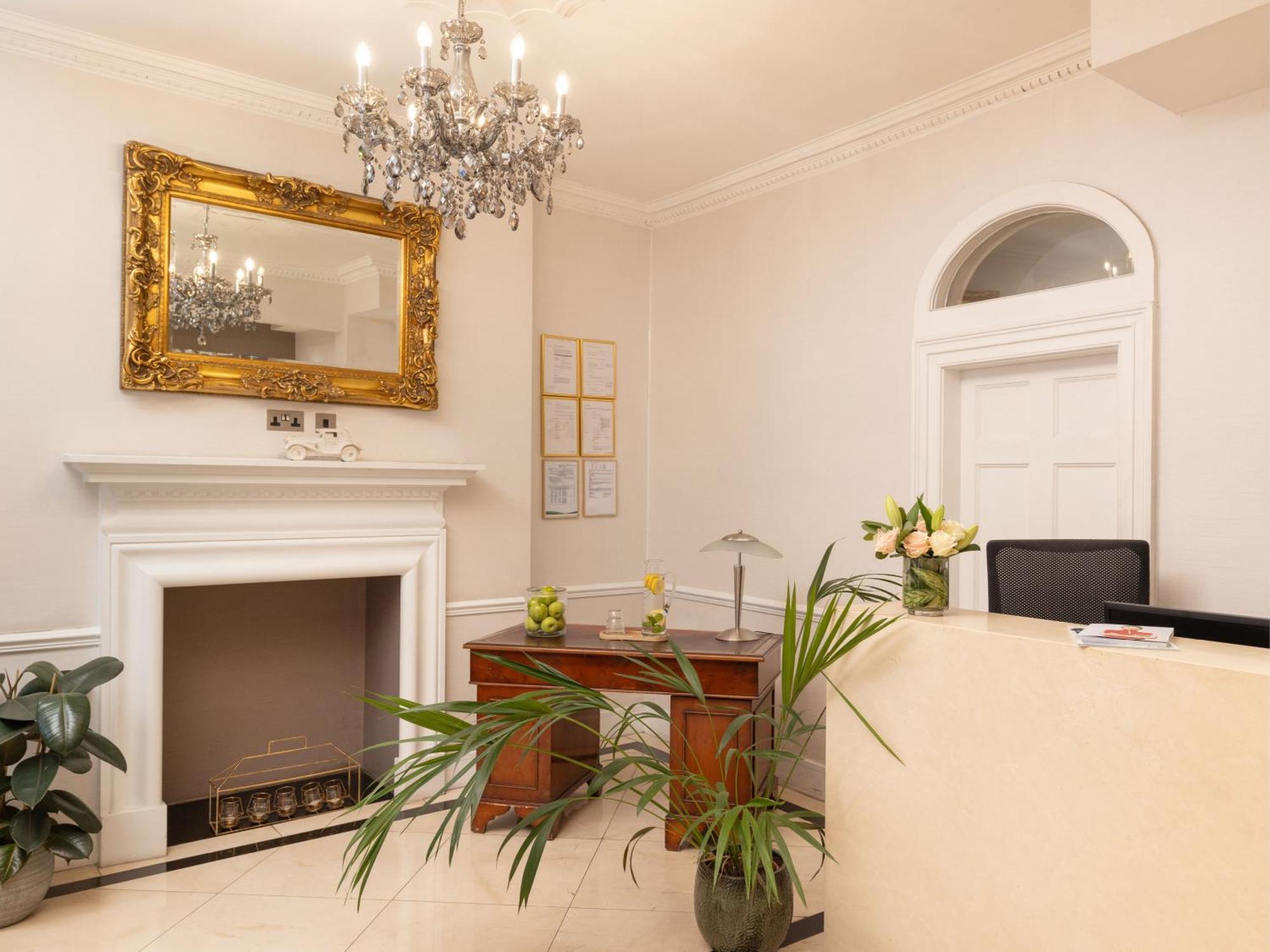 Hotel Montcalm Brewery Townhouse Londýn Exteriér fotografie The photo shows a stylish reception area. There is a decorative chandelier hanging from the ceiling, providing elegant lighting. A large, ornate mirror is mounted on the wall beside the fireplace, which features a simple, classic design. In front of 